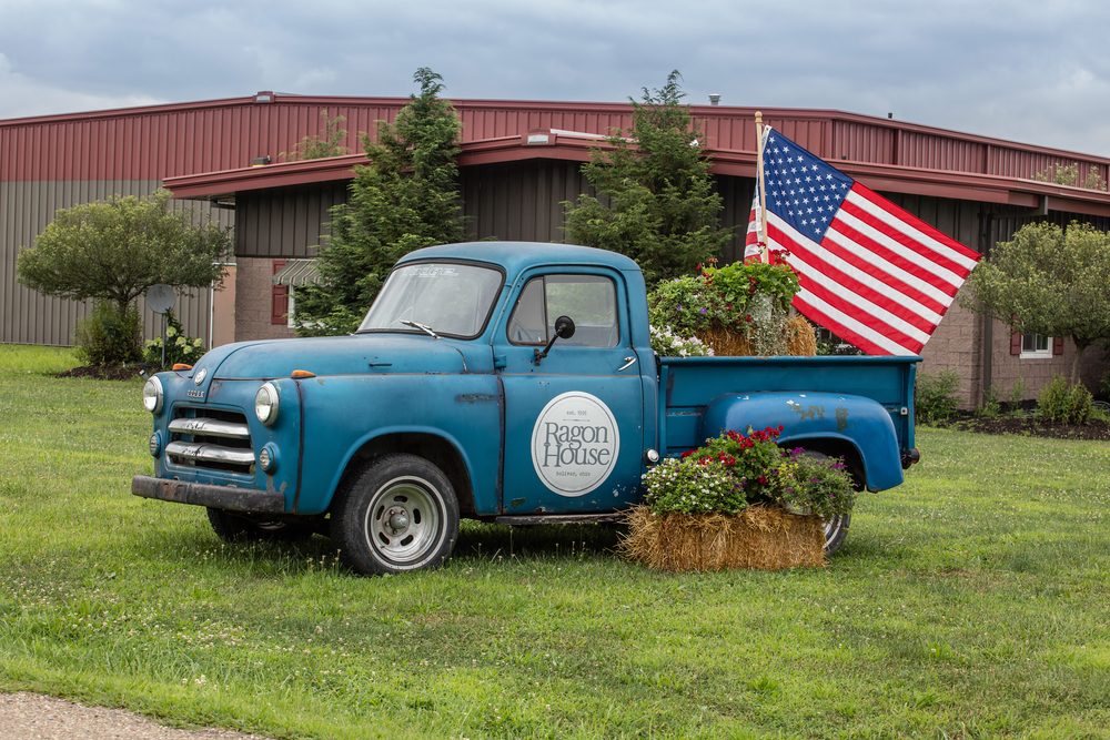 Vintage blue Ragon House truck with an American flag outside the warehouse